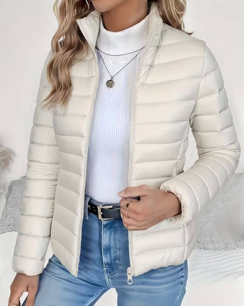 Front view showing stand collar, zip closure and quilted body, cream