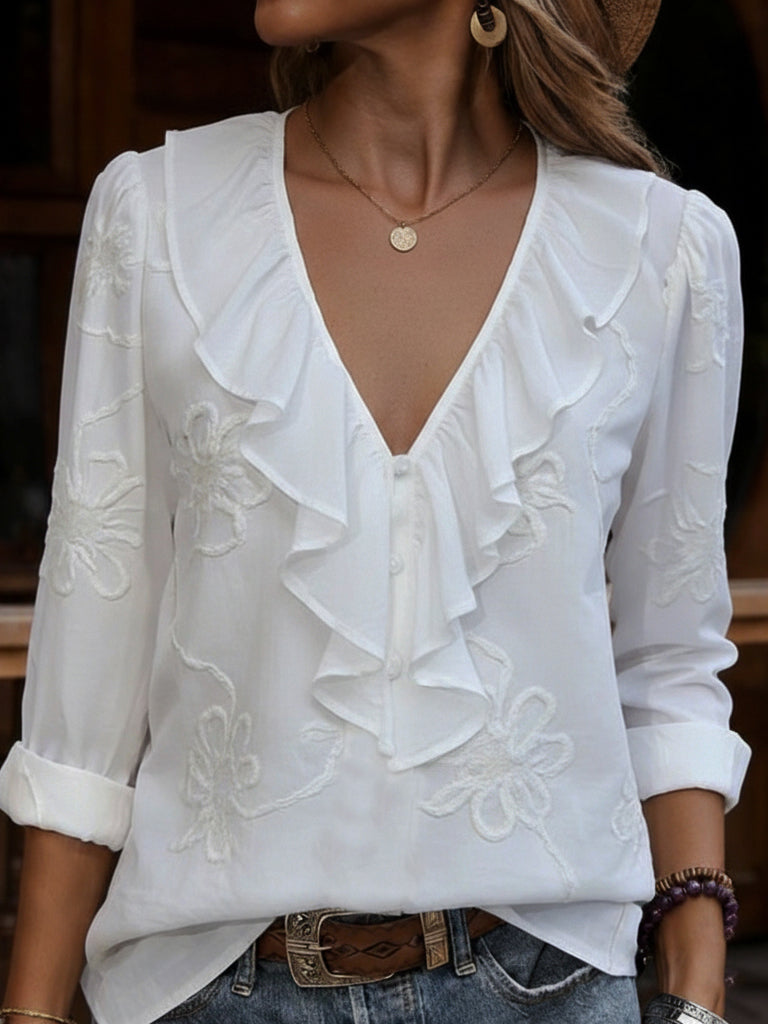 Front view of deep v-neckline with ruffle trim, button placket and floral embroidery, white