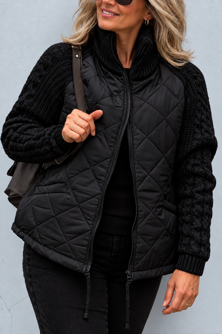 Front view showing stand collar, cable sleeves, quilted body and front zip with toggles, black