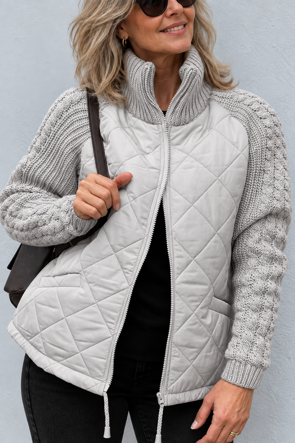 Front view showing stand collar, cable sleeves, quilted body, side pocket and drawstring hem, grey