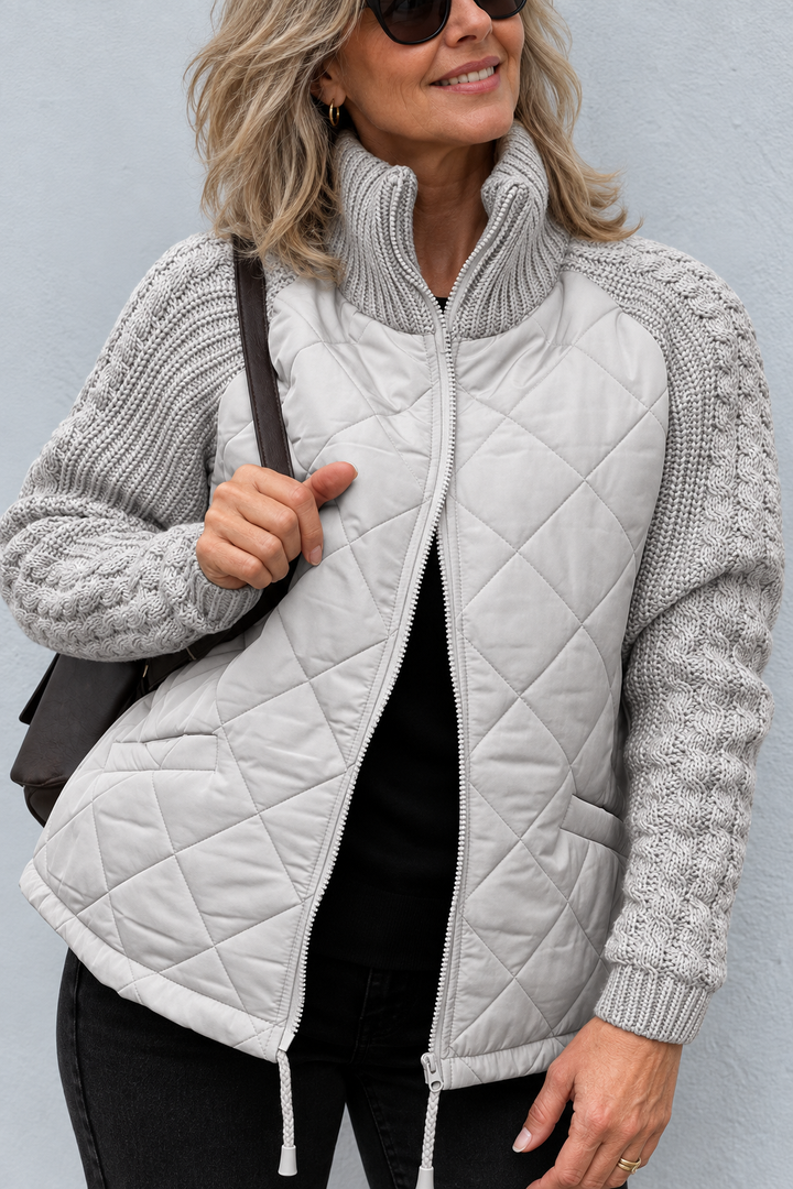 Front view showing stand collar, cable sleeves, quilted body, side pocket and drawstring hem, grey